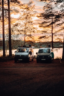 A fleet of diverse vehicles including vans and cars lined up outside a film set during sunset.