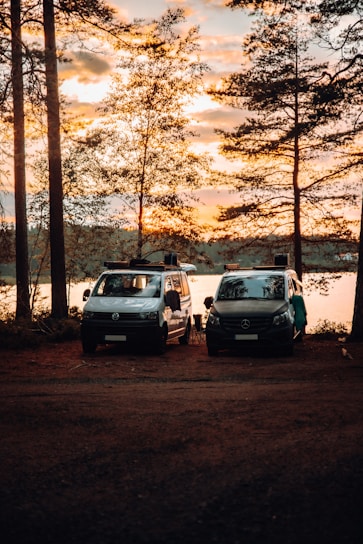 A fleet of diverse vehicles including vans and cars lined up outside a film set during sunset.