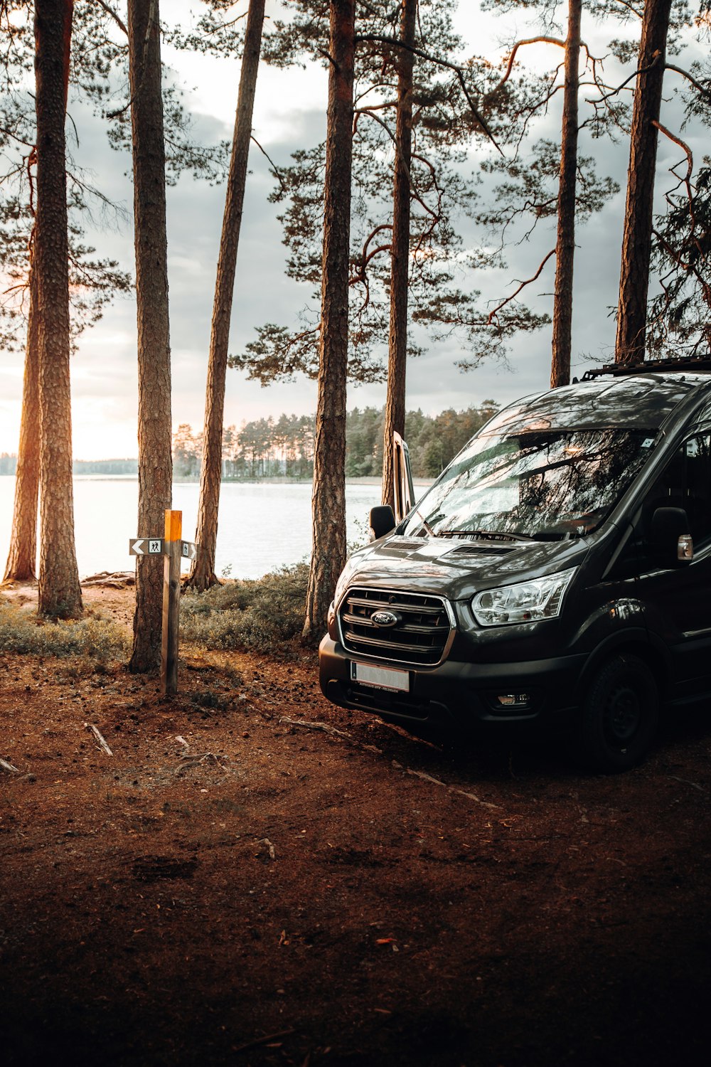 a van parked in a wooded area next to a body of water