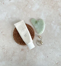A serene flat lay of glovera’s nourishing cream and face washes on a soft cream and sage green background with matte gold accents.
