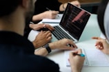 a group of people sitting around a laptop computer