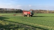 A modern agricultural sprayer machine working in a green field under a clear sky