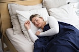 a woman sleeping on a bed with a blue blanket