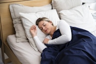 a woman sleeping on a bed with a blue blanket