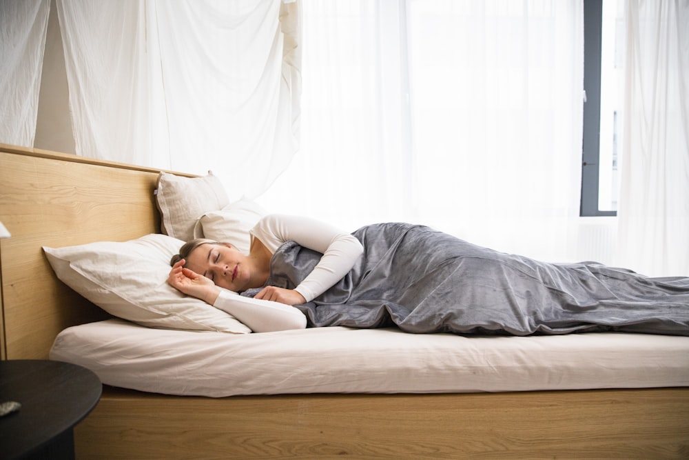 a man laying on a bed with a blanket on top of it