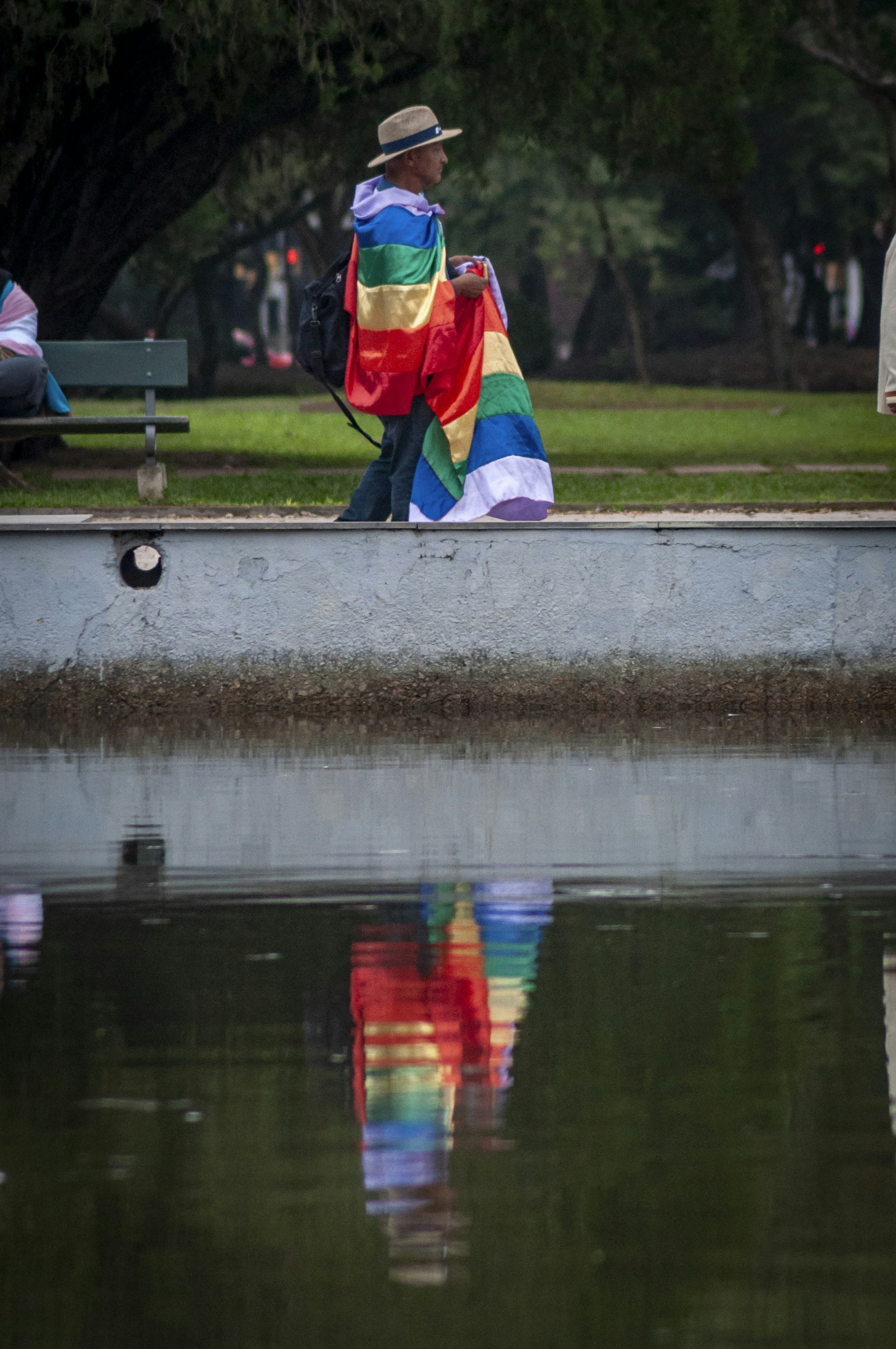 a man sitting on a bench next to a body of water