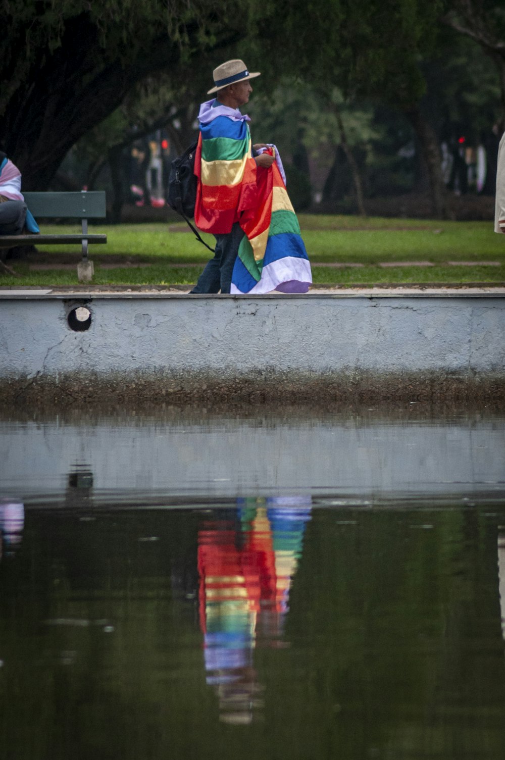 a man sitting on a bench next to a body of water