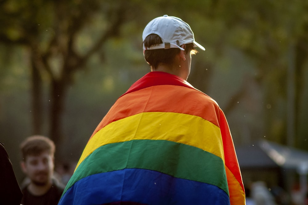 um homem vestindo uma jaqueta colorida de arco-íris e chapéu