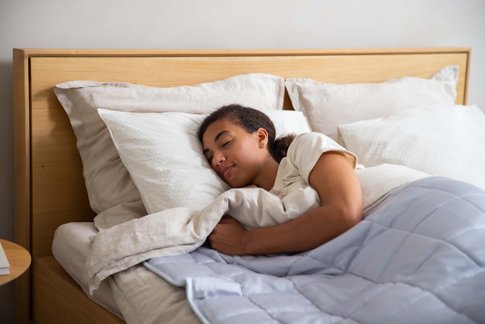 a young girl sleeping in a bed with white sheets