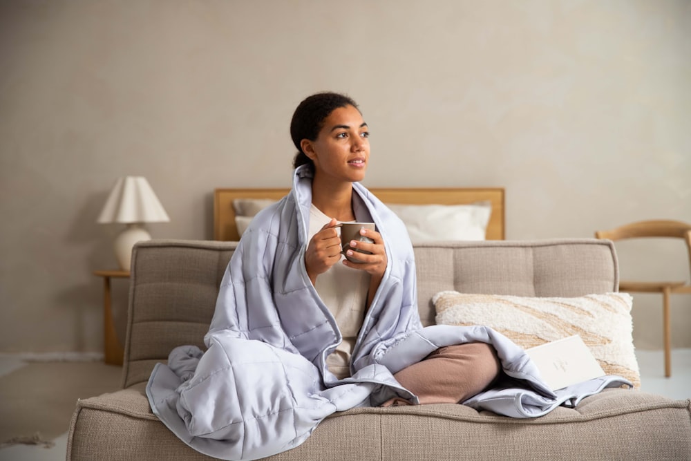 a woman sitting on a couch holding a cup of coffee