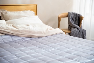 A bedroom with a neatly made bed featuring a wooden headboard and soft linens.