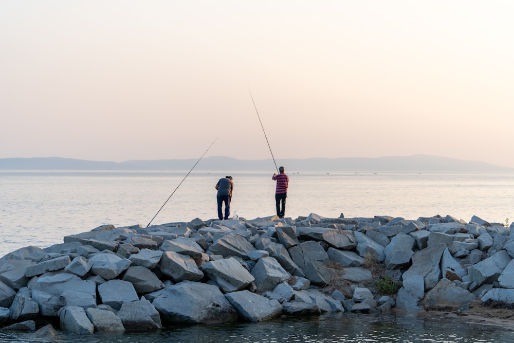 a couple of men standing on top of a pile of rocks