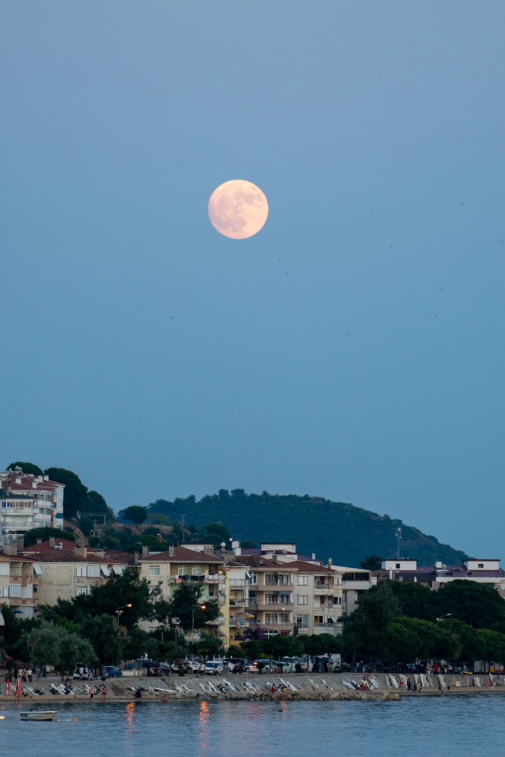 a full moon rising over a city on a hill