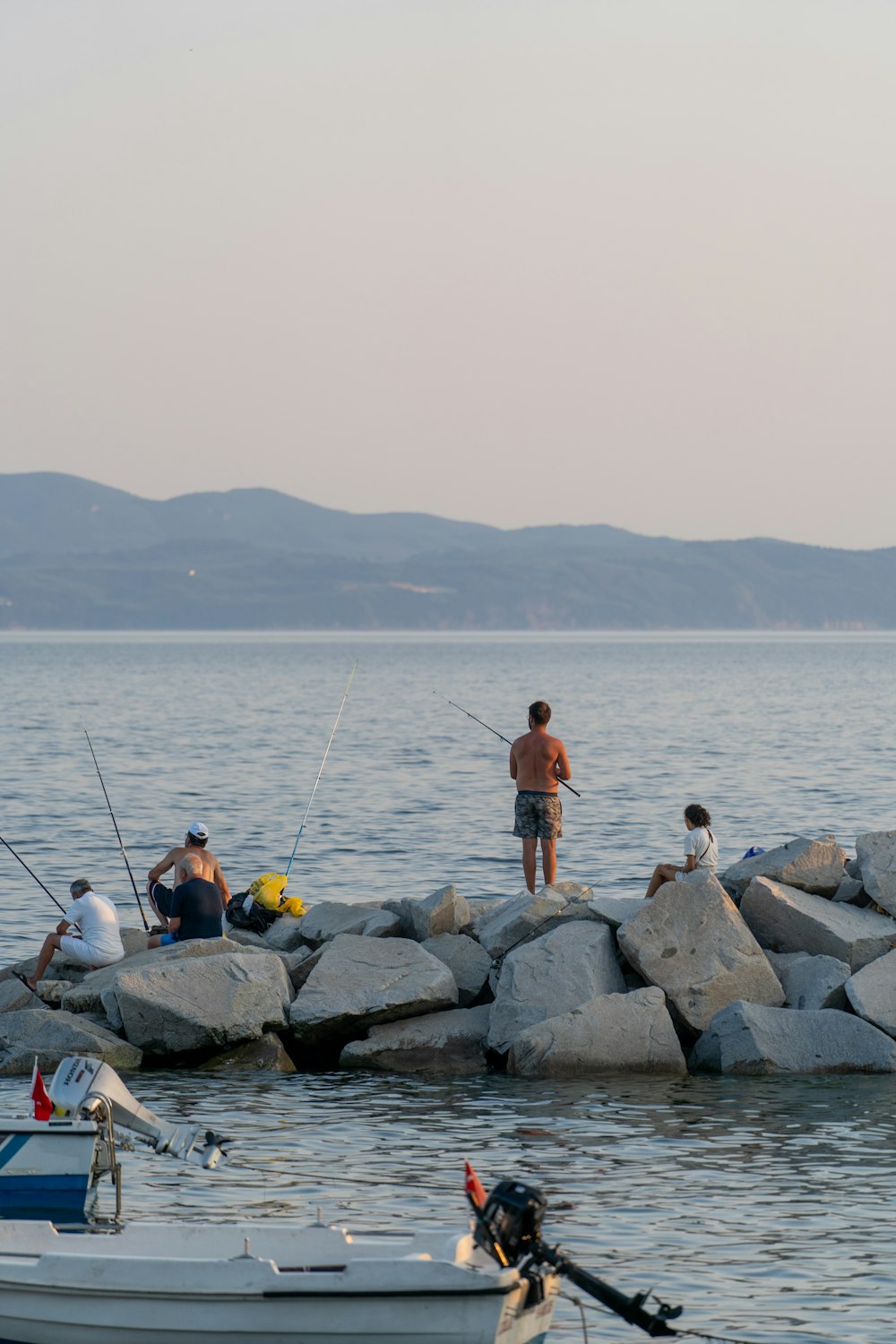 a group of people fishing off of rocks in the water