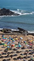 A lively beach scene at Copacabana with people playing volleyball and relaxing under umbrellas.