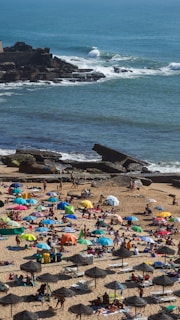 A lively beach club scene with people enjoying the sun and sea under stylish umbrellas.