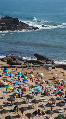 A lively beach scene with families playing, colorful umbrellas, and gentle waves.