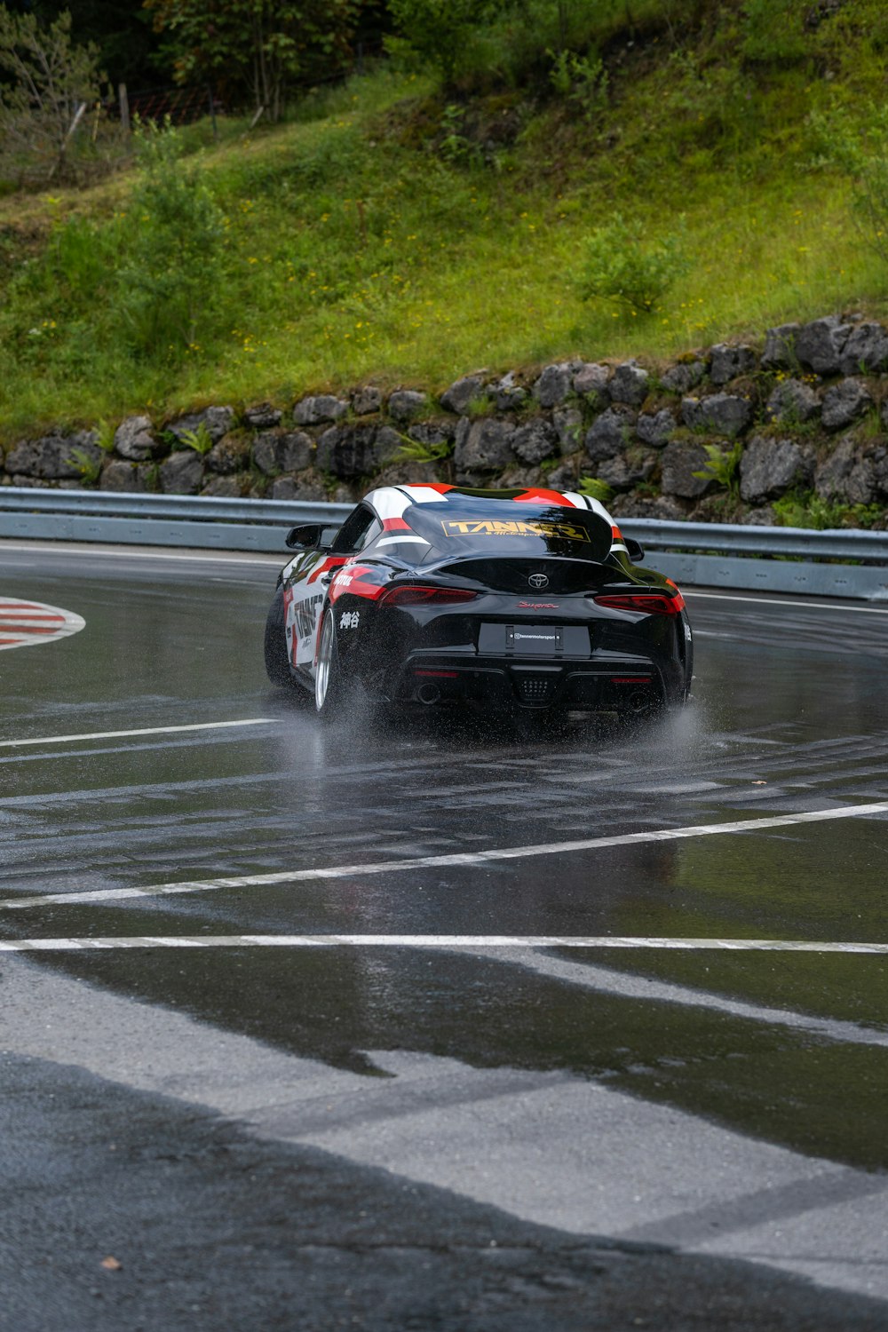 a black sports car driving on a wet road