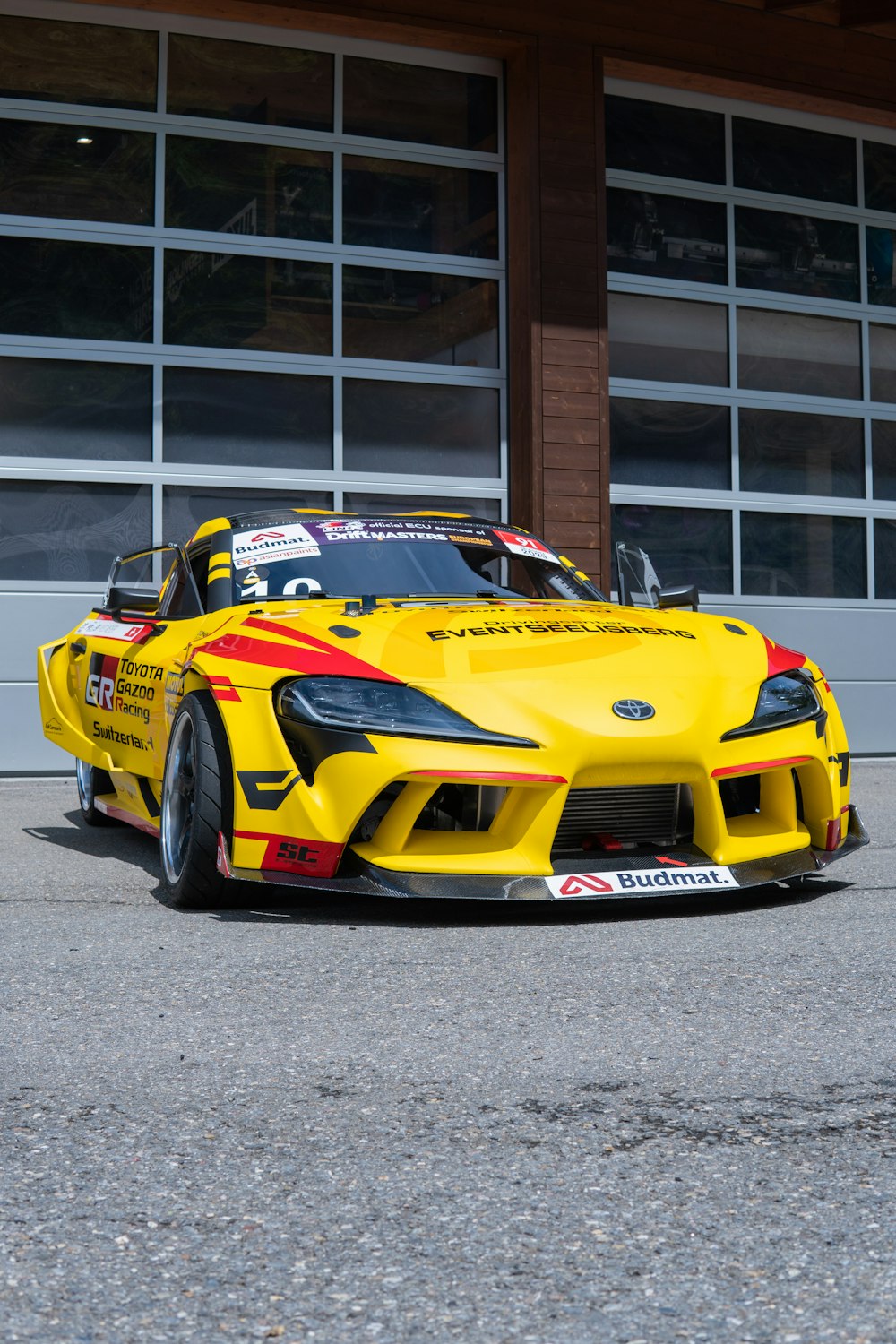 a yellow sports car parked in front of a garage