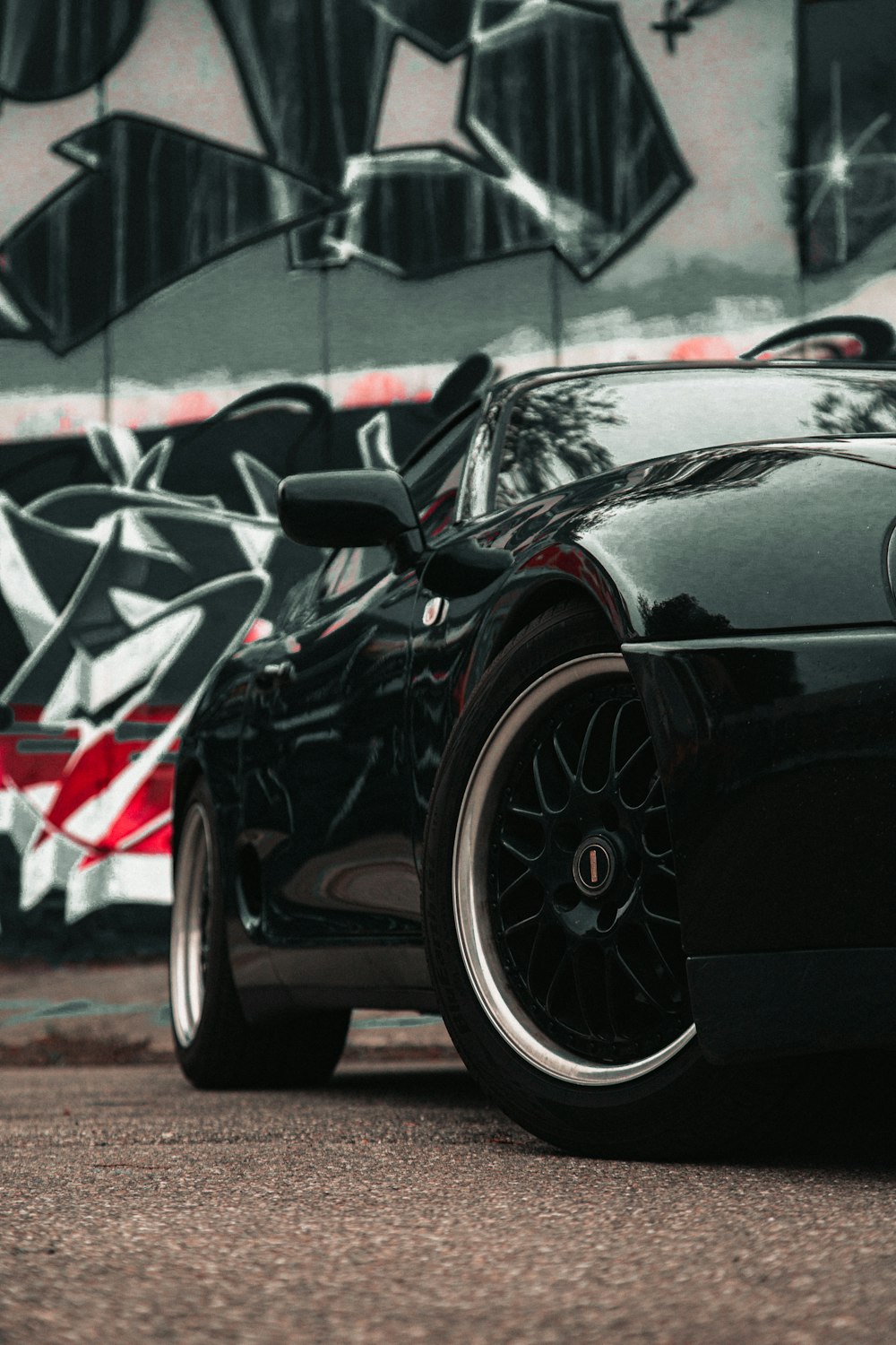 a black sports car parked in front of a graffiti covered wall