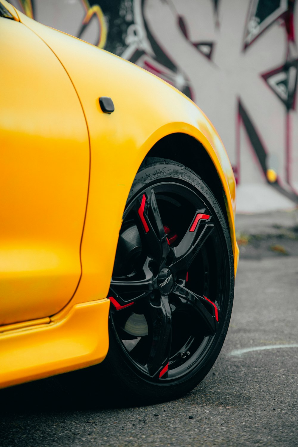 a yellow sports car parked in front of a graffiti covered wall