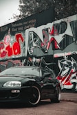 A side view of a trendy car model cruising past urban graffiti walls.