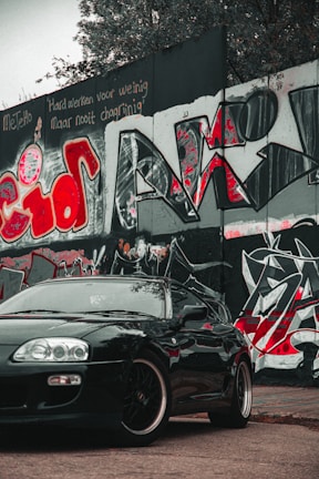 A side view of a trendy car model cruising past urban graffiti walls.