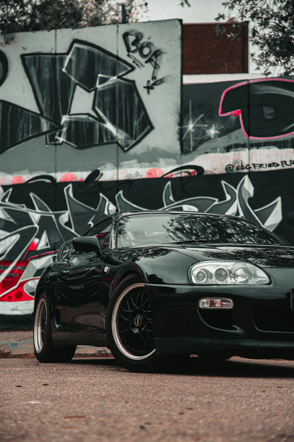 a black sports car parked in front of a graffiti covered wall