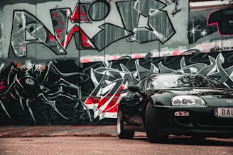 A dynamic street scene featuring a sleek car with bold graffiti art in the background, capturing the edgy spirit of Fatigang.
