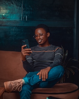 A smiling person browsing digital articles on a smartphone in a cozy setting.