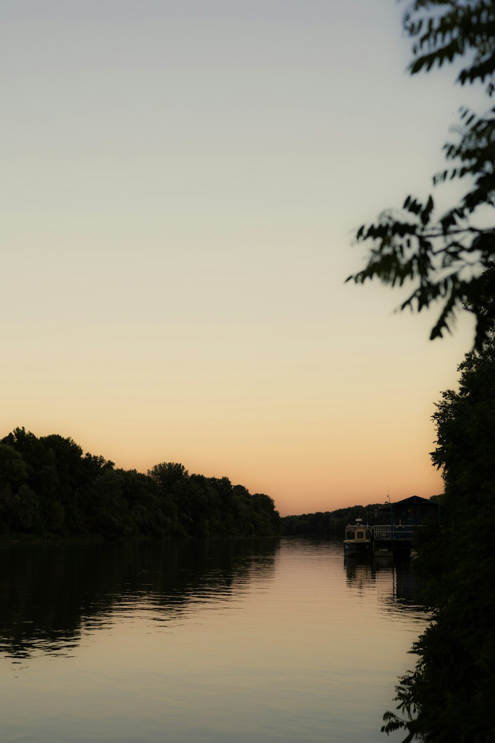 a body of water surrounded by trees at sunset