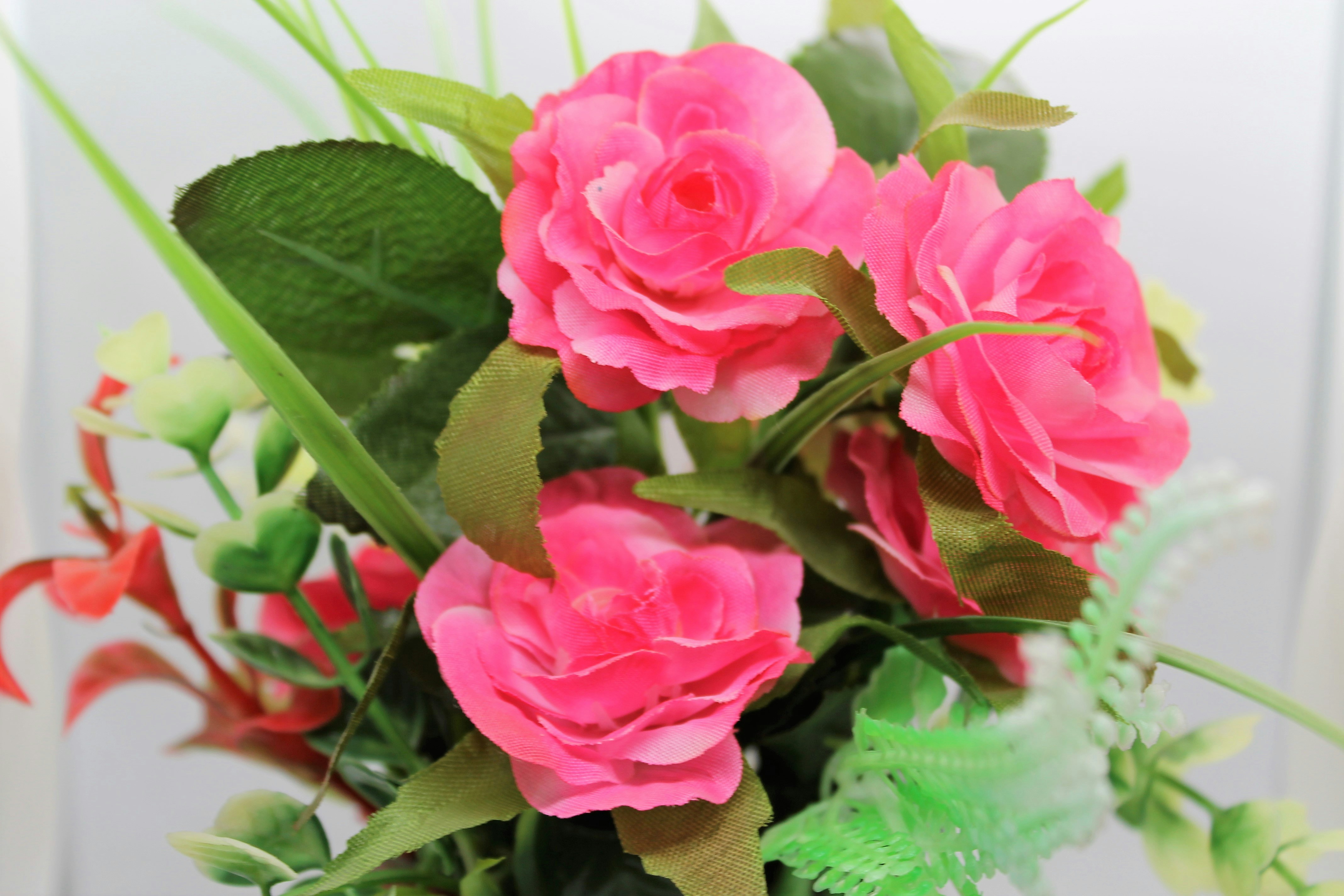 a vase filled with pink flowers and green leaves