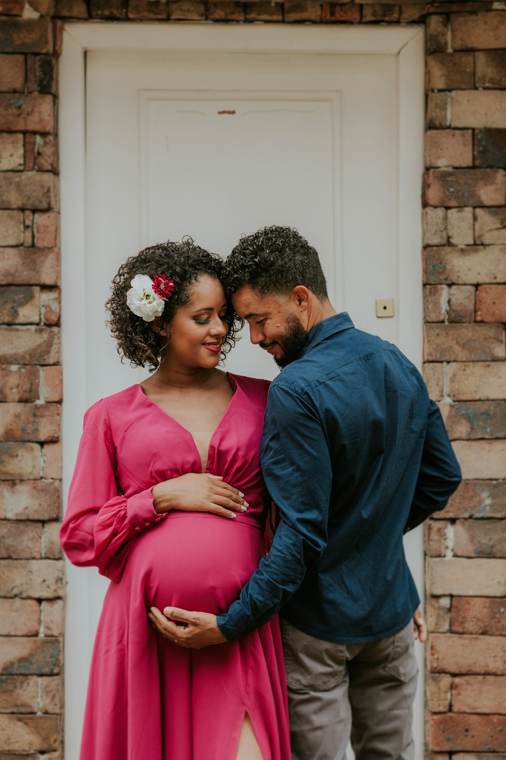 a pregnant couple standing in front of a door