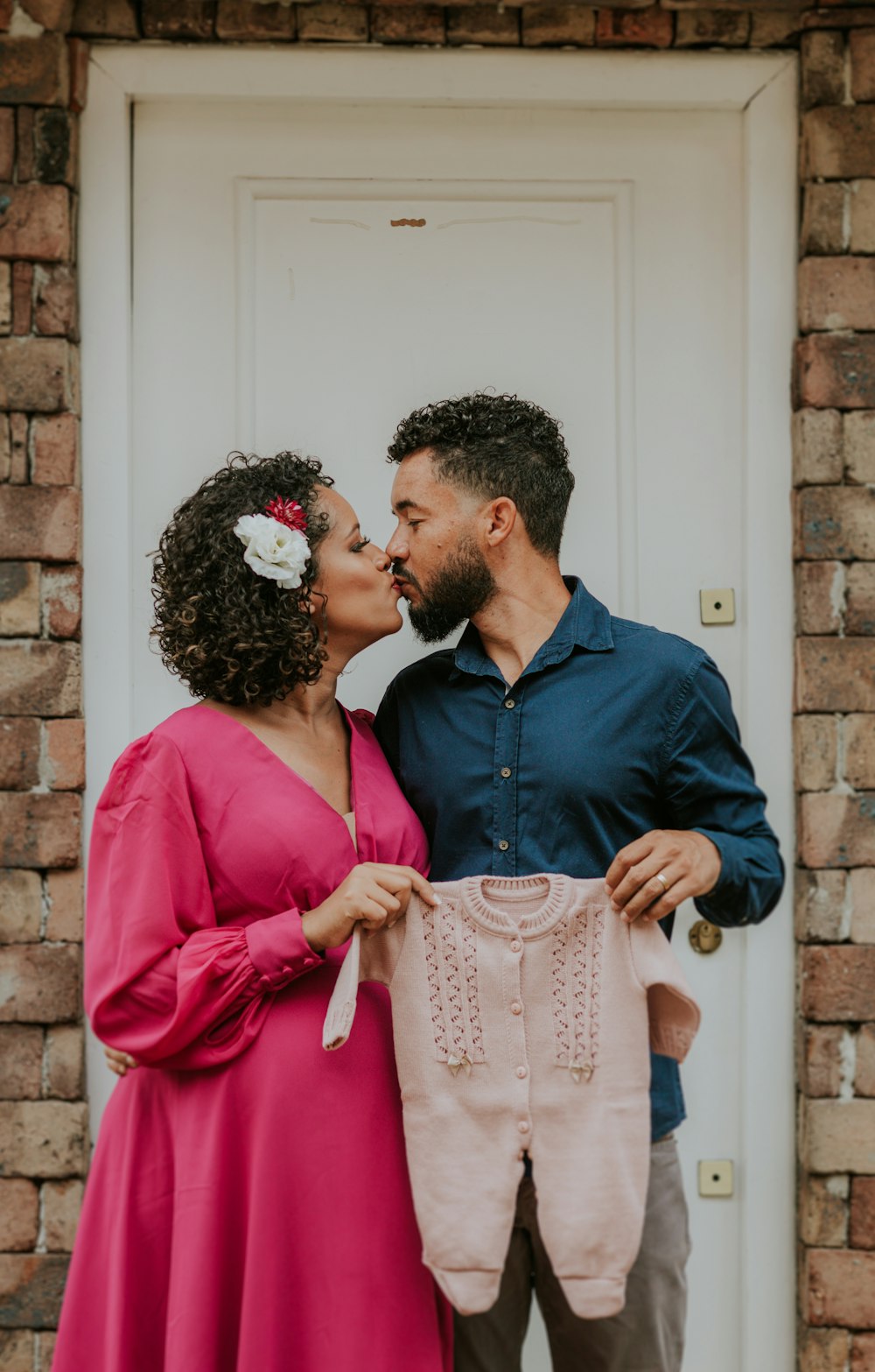 a man and a woman kissing in front of a white door