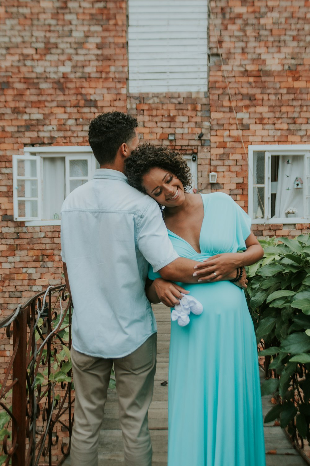 a pregnant woman in a blue dress standing next to a man in a white shirt