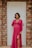 a woman standing in front of a door wearing a pink dress