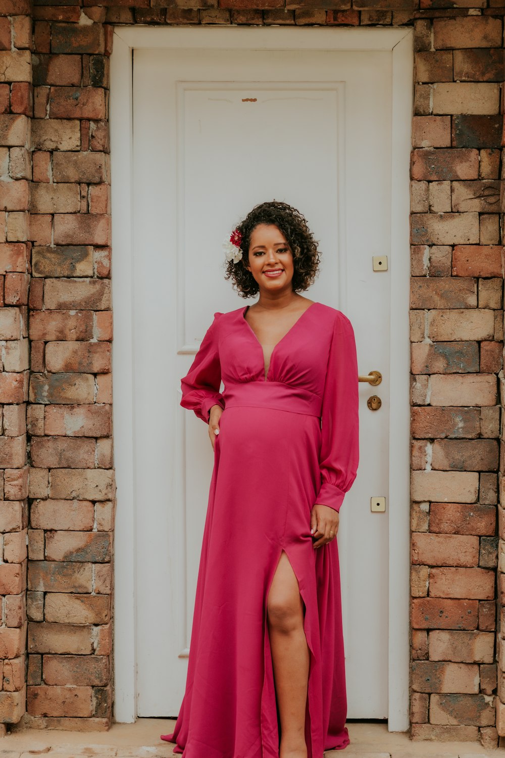 a woman standing in front of a door wearing a pink dress