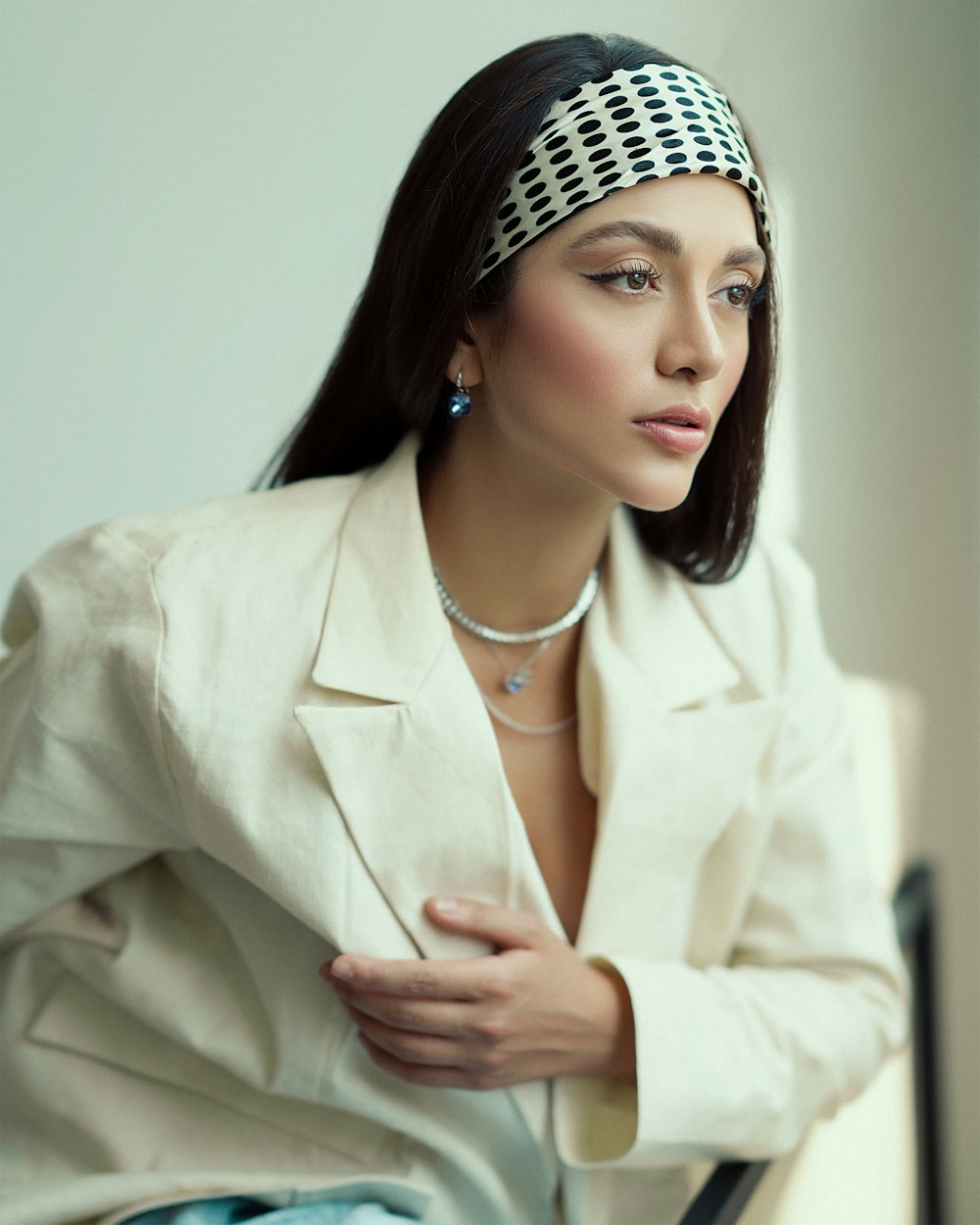 a woman sitting on a chair wearing a white jacket