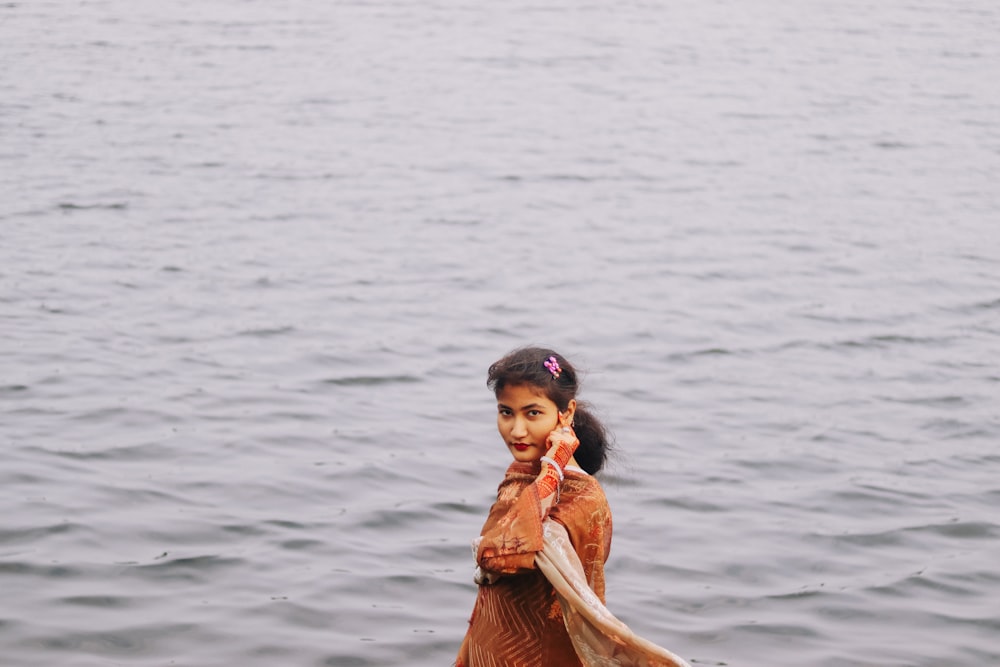 a young girl standing in the water with a fish in her hand