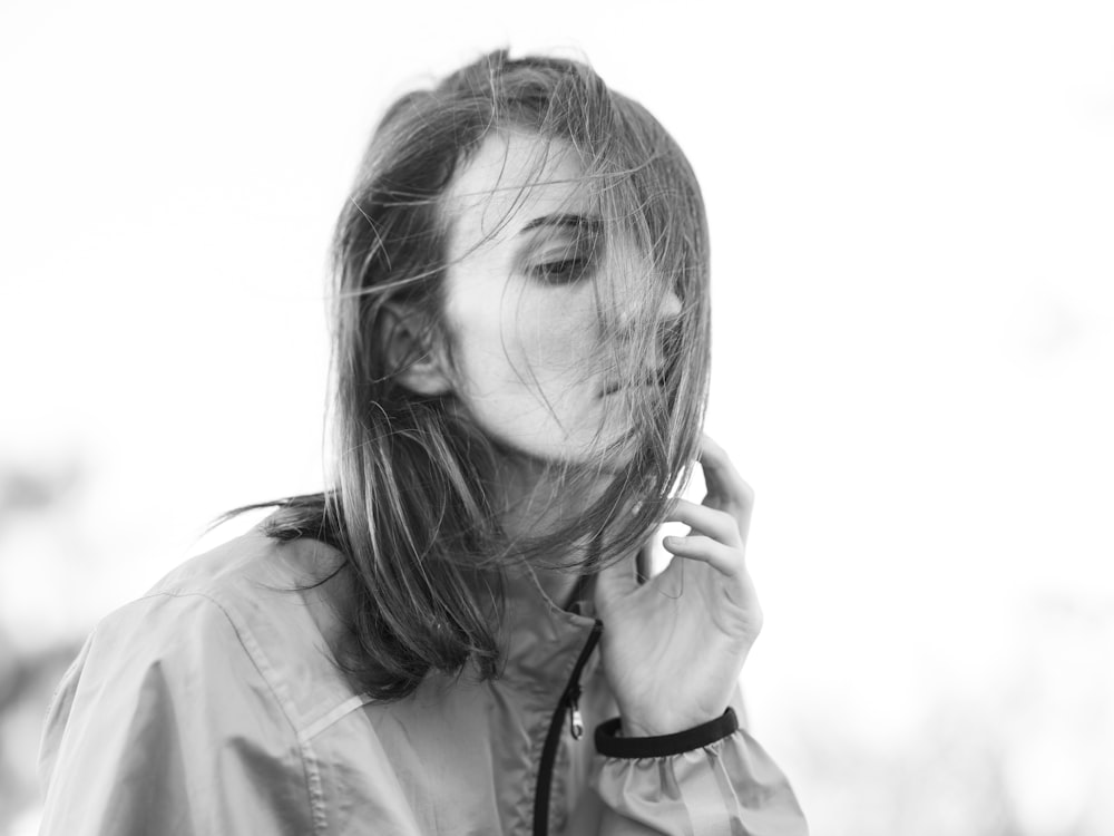 a black and white photo of a woman with her hair blowing in the wind