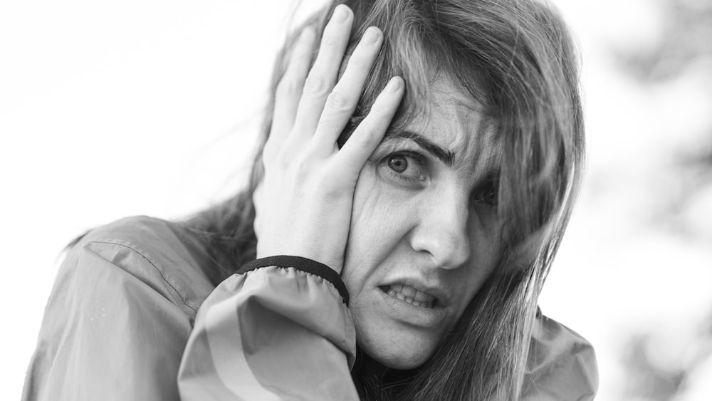 a black and white photo of a woman covering her face