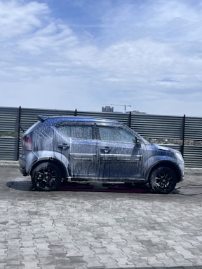 A mobile steam car wash van parked beside a clean, shiny car in a sunny urban setting.