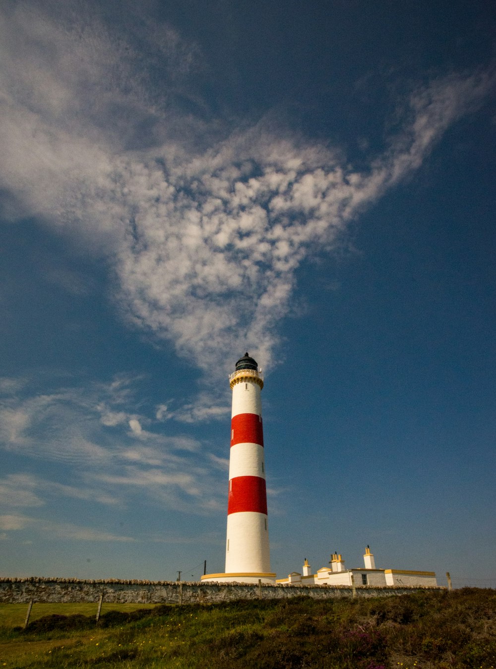 a red and white lighthouse sitting on top of a lush green field