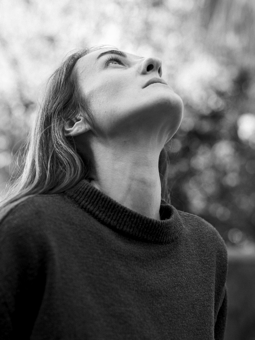 a black and white photo of a woman looking up