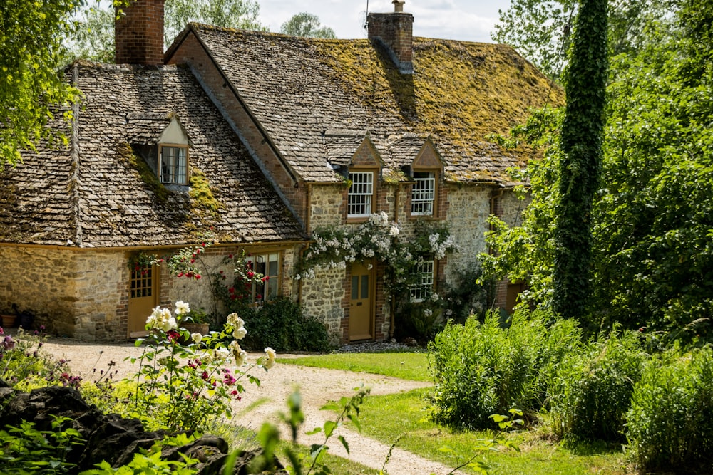 a stone house with a green roof surrounded by greenery