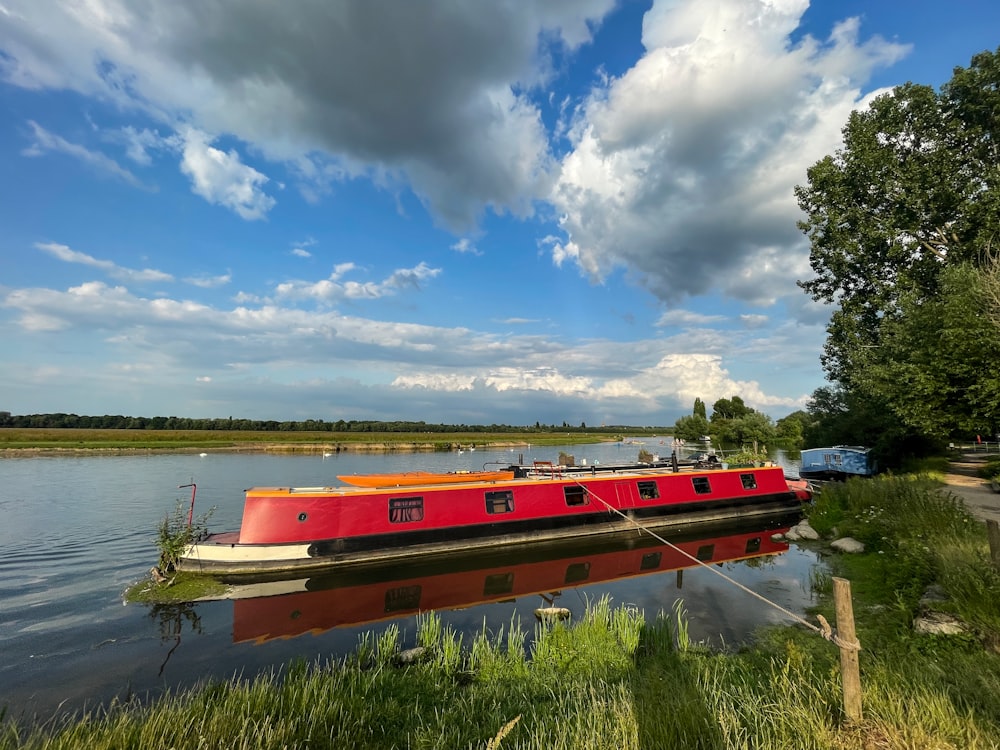 a large red boat floating on top of a river