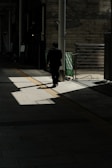 A shadowy figure being followed discreetly through a busy urban street.