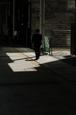 A shadowy figure being followed discreetly through a busy urban street.