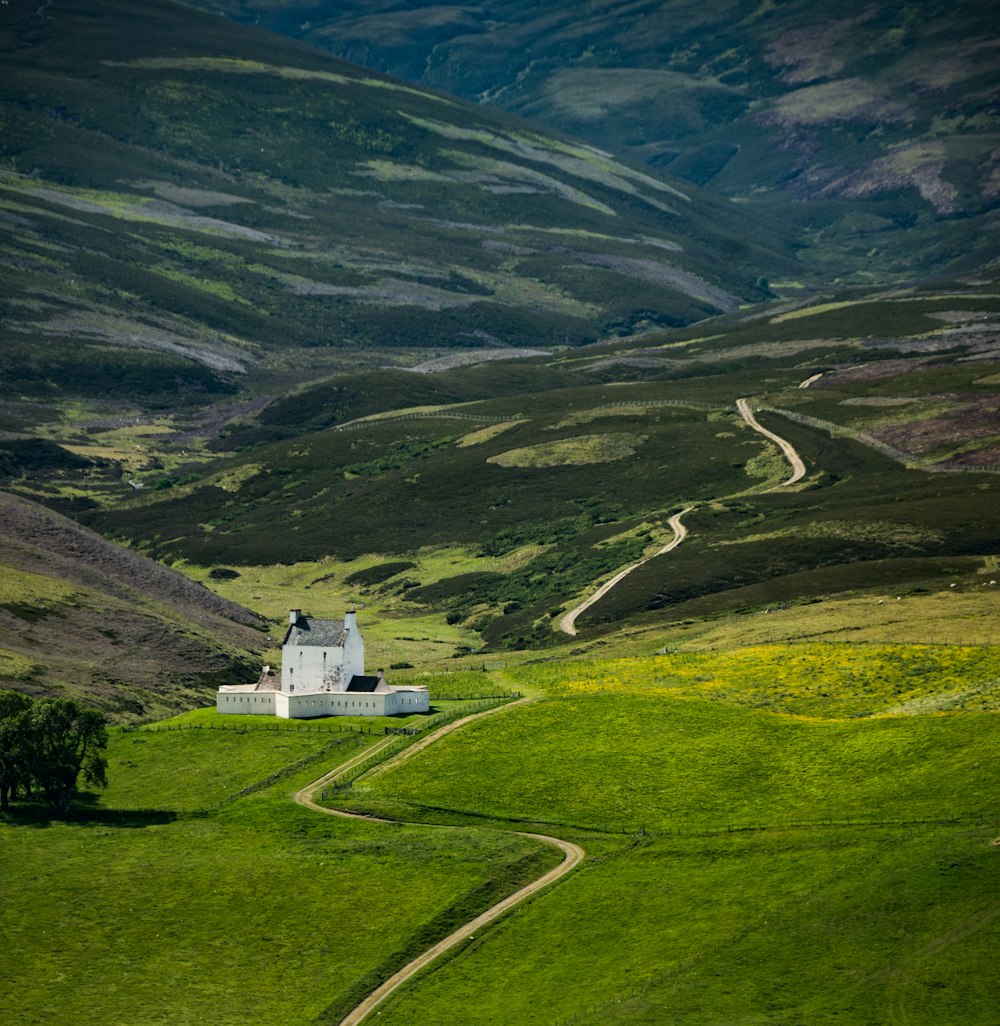 a house in the middle of a lush green valley