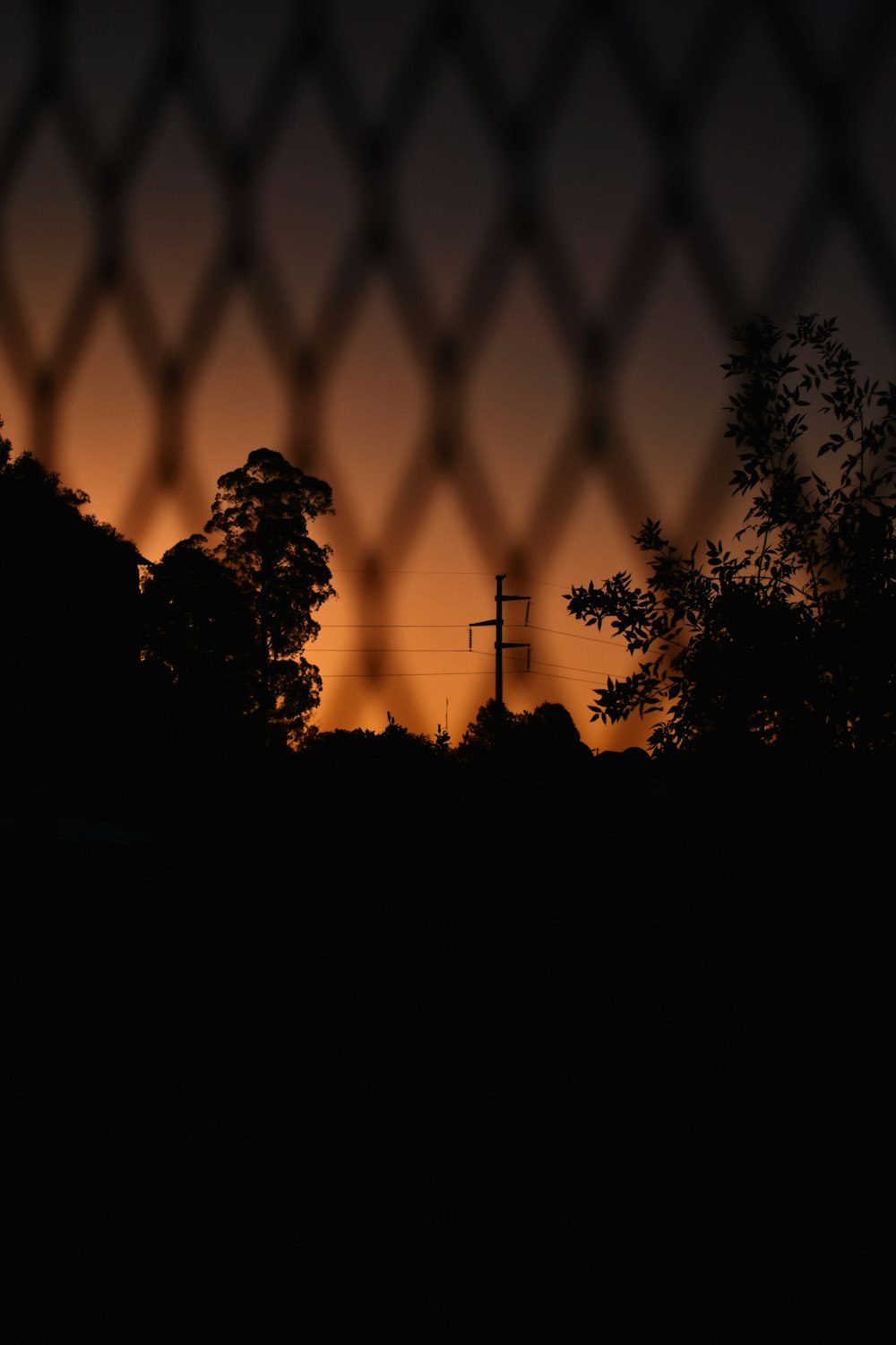 Una vista de una puesta de sol a través de una cerca de alambre